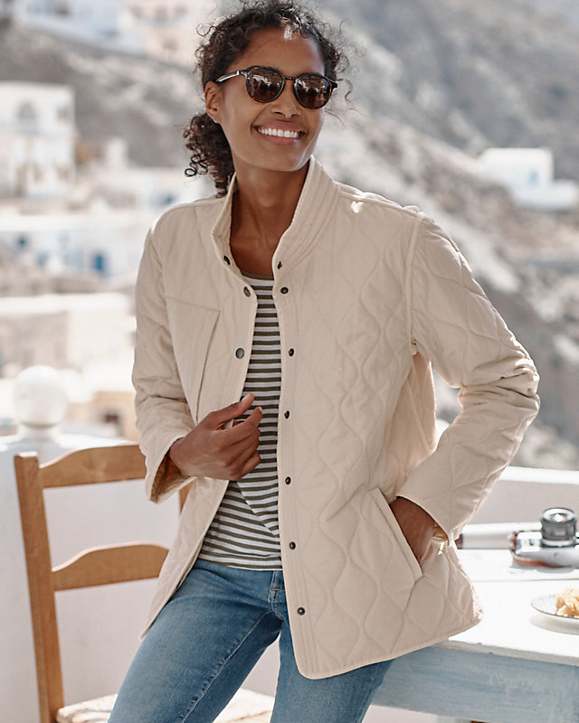 A woman in a white recycled quilted field jacket. Shop women's coats & jackets.